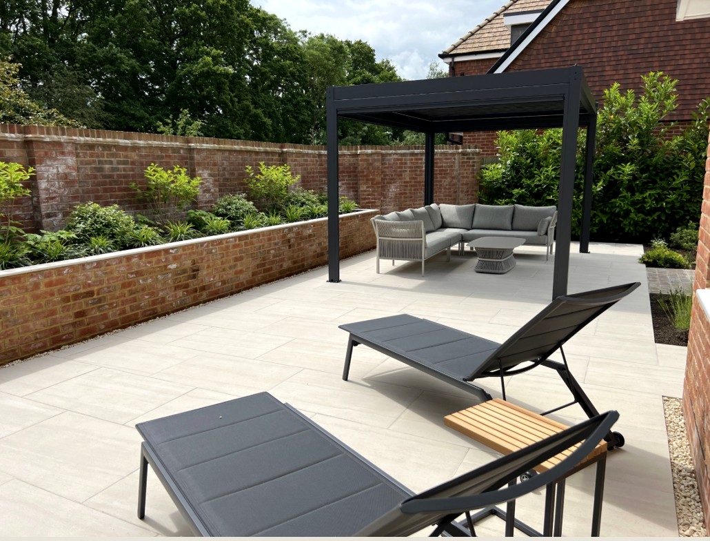 Lounge chairs on a tiled patio with a Louvara pergola and seating beyond