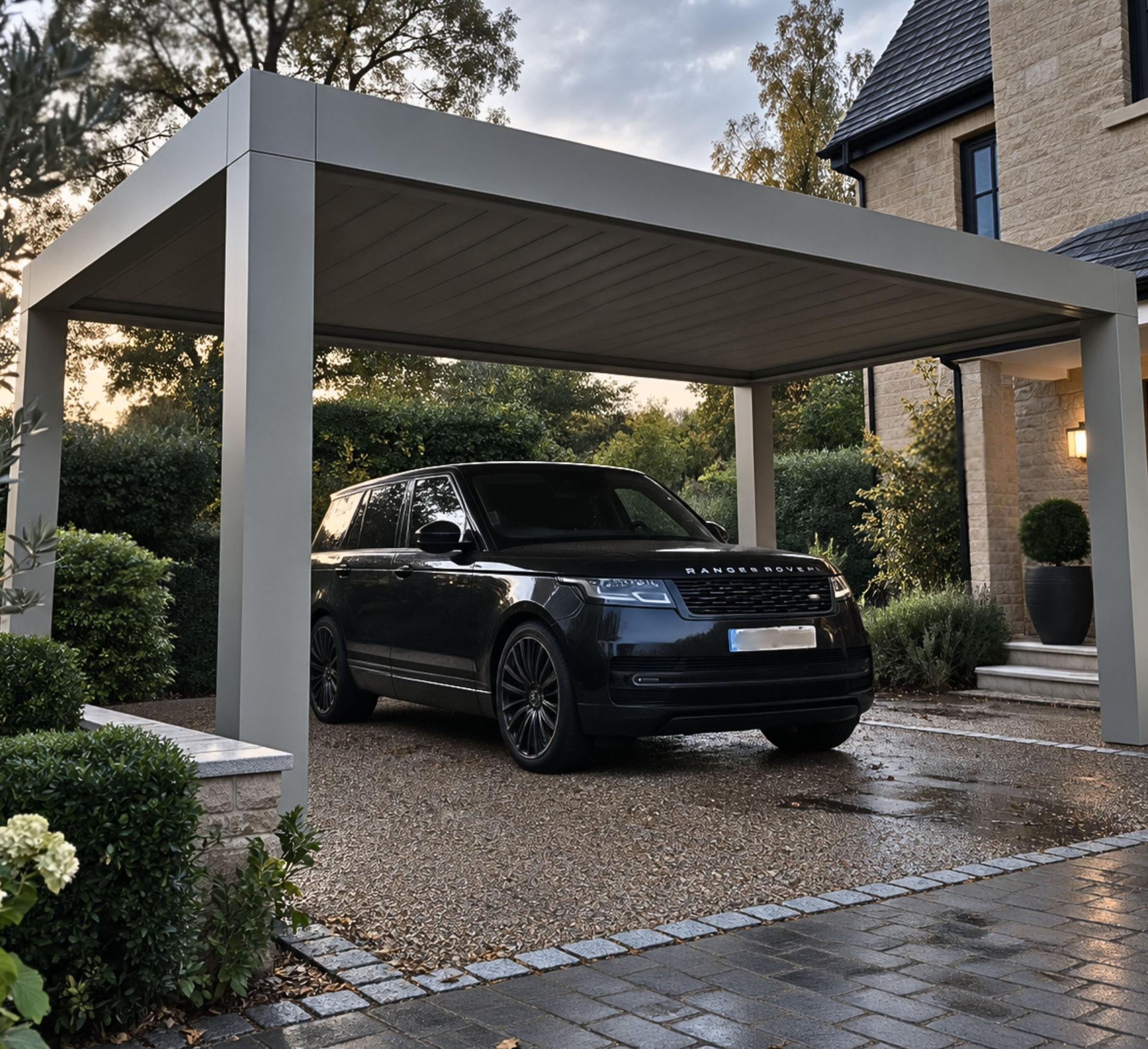 Louvara flat-roofed aluminium car port sheltering a car on a gravel driveway beside a stone house